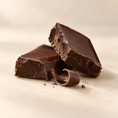 Representative two broken pieces of rich dark chocolate with a small delicate curl of chocolate imagery for fragrance-note discovery