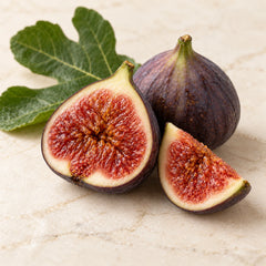 Illustration of whole and cut ripe figs with a fig leaf representing the fig fragrance note