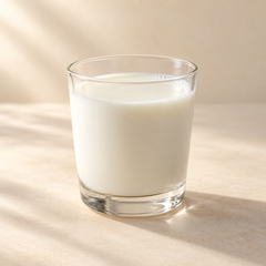 Representative a small clear glass of fresh white milk with a subtle milk surface meniscus imagery for fragrance-note discovery